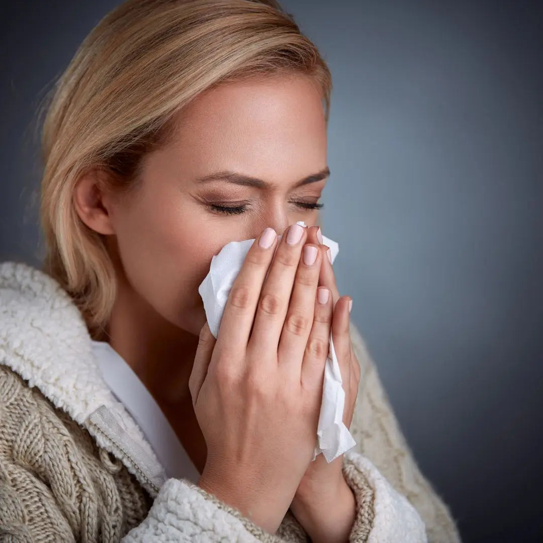 Persona estornudando mientras se protege con un pañuelo, imagen representativa de los productos antigripales naturales de Alternativ para apoyar el bienestar durante la temporada de resfriados.